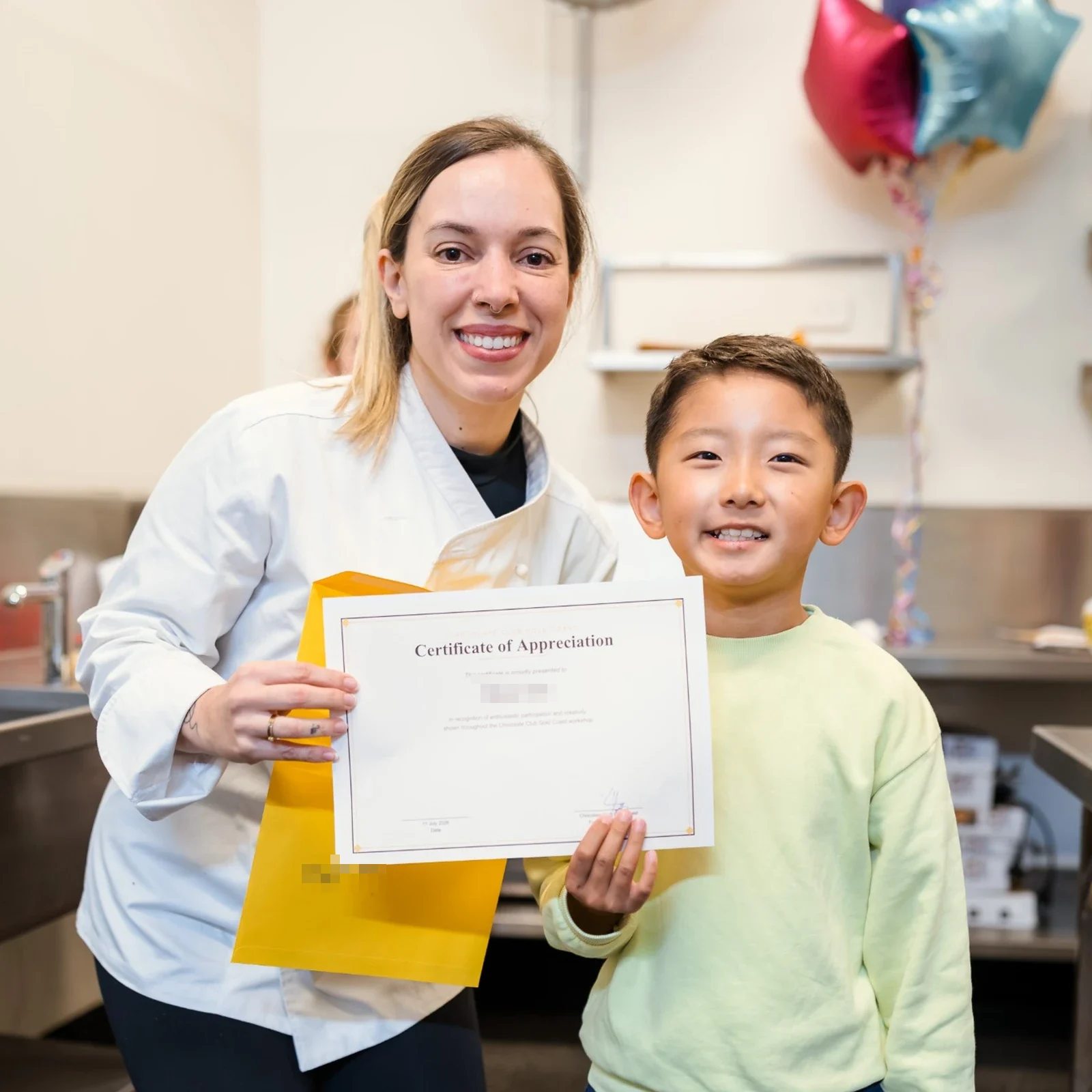 A Care & Culinary chef with a smiling young participant holding his certificate