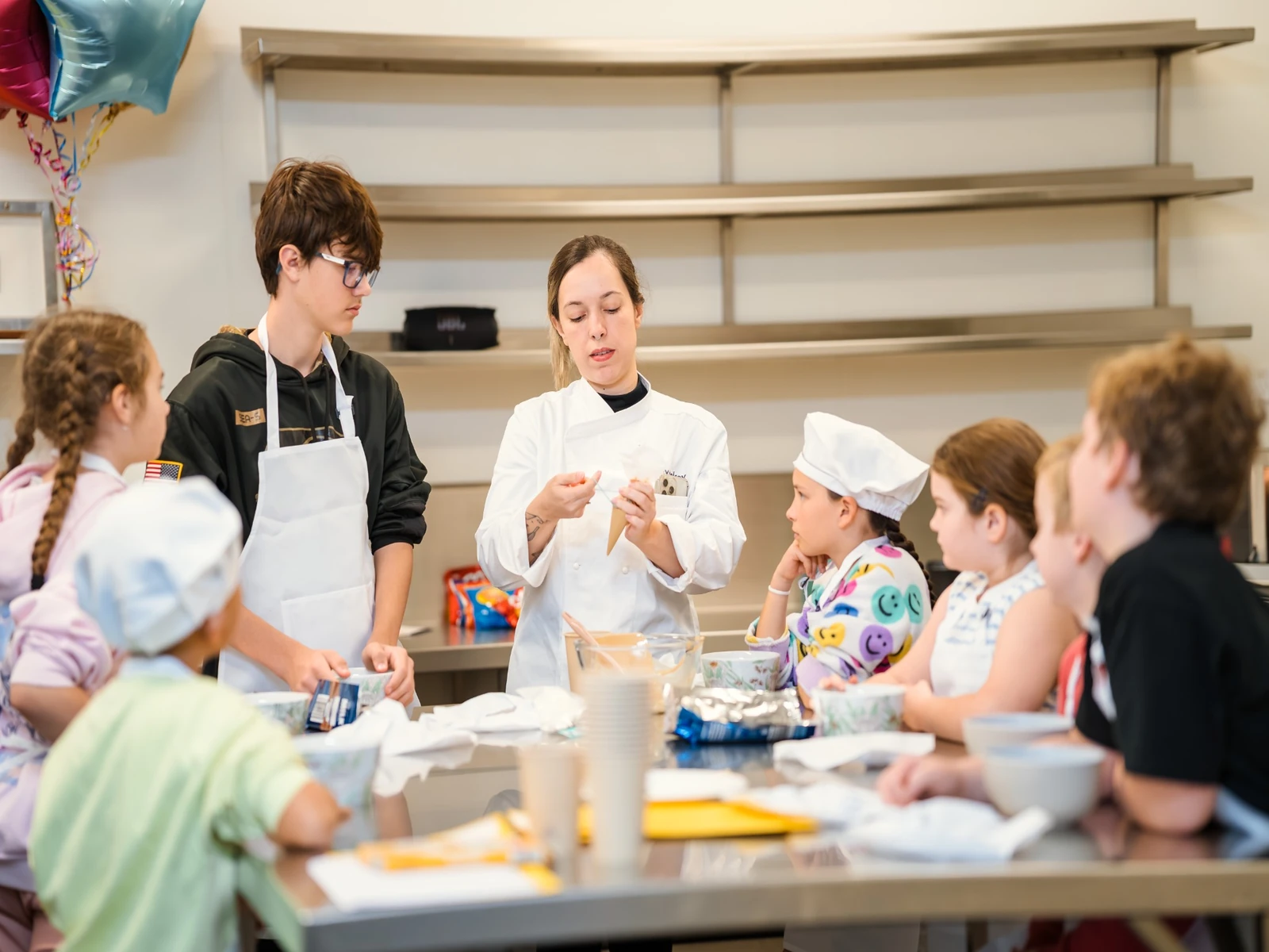 A Care & Culinary chef showing a group of children how to use a piping bag